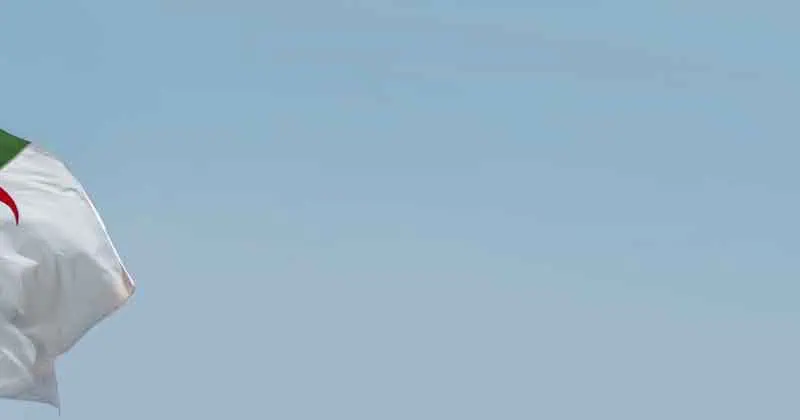 Algerijnse vlag wappert in de wind tegen een blauwe lucht.